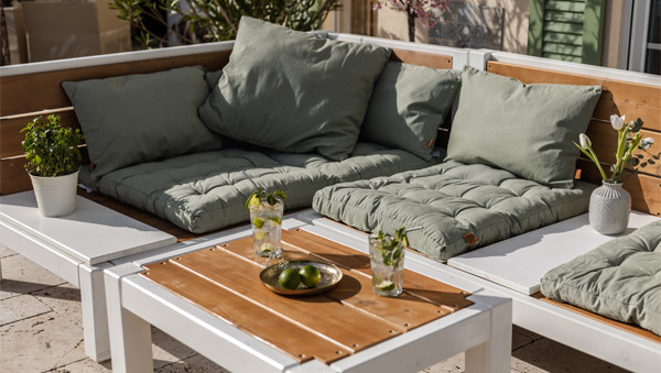 Gartenlounge mit Gartentisch und grünen Kissen