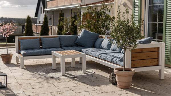 Große Lounge auf Terrasse mit blauen Kissen und Pflanzen